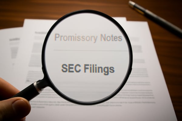 A magnifying glass closely examines legal documents to symbolize the importance of due diligence in financial and real estate investments.